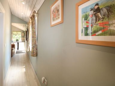 A hallway with wall art windows with curtains and wooden ceiling leading to a kitchen area at The Hen House in Stockwell Heath near Rugeley