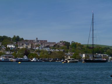 A view of boats on water with houses and a large building on a hillside in the background at Orchard Loft in Brownston near Modbury