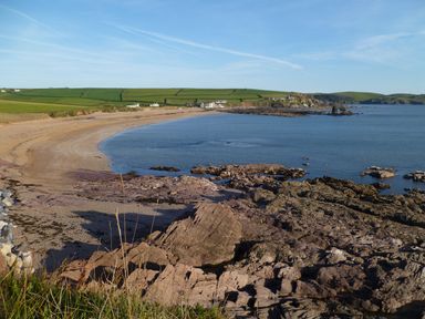 A coastal landscape with a sandy beach rocky shore and green fields at Orchard Loft in Brownston near Modbury