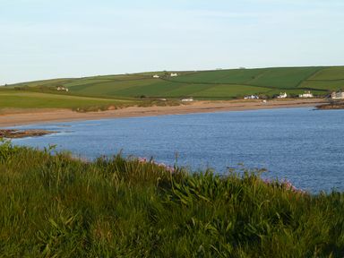 A coastal landscape with a beach water and green fields with scattered houses at Orchard Loft in Brownston near Modbury