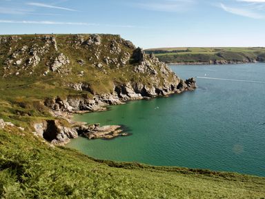 Rocky coastal cliffs with green vegetation and a bay with clear water at Orchard Loft Brownston near Modbury