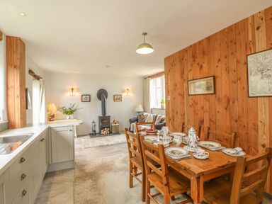 A kitchen and dining area with a wooden table set for tea and a wood-paneled wall at The Old Laundry in North Tawton