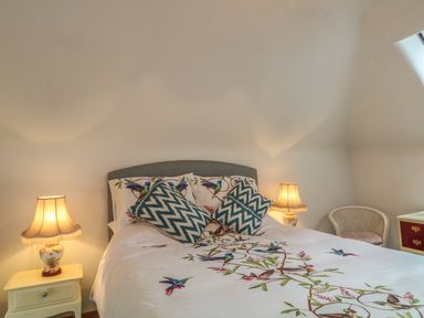 A bedroom with a bed two bedside tables with lamps a chair and a dresser at The Old Laundry in North Tawton