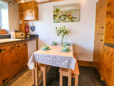 A kitchen with a table set for meals at Woodland Cottage in Garth