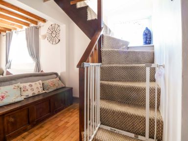 A staircase with a safety gate and a sofa at Woodland Cottage in Garth