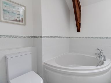 A bathroom with a toilet and a corner bathtub with a handheld shower at Nuke in Weymouth