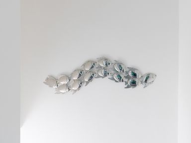 A white wall with a decorative installation of metallic fish at Nuke in Weymouth