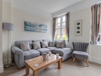 A living room with gray sofa and chair wooden coffee table and windows with curtains at Nuke in Weymouth