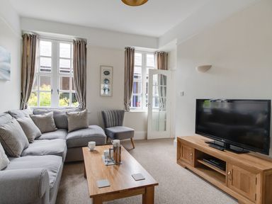 A living room with a gray sofa a wooden coffee table a gray chair and a television on a wooden stand at Nuke in Weymouth