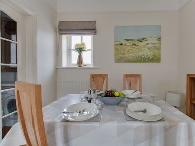 A dining room with a table set for four with plates and cutlery and a bowl of fruit on the table at Nuke in Weymouth