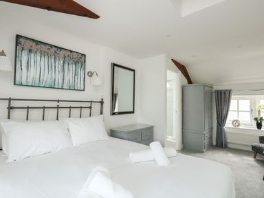 A bedroom with a bed white bedding gray furniture and a window with curtains at Nuke Weymouth