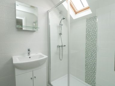 A bathroom with a sink cabinet mirror and a glass shower enclosure with a skylight at Nuke in Weymouth