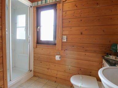 A bathroom with a shower cabin a window a toilet and a sink at Heron Lodge in Badwell Ash