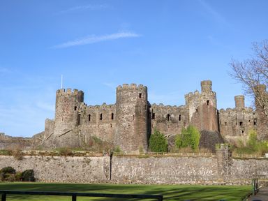 An exterior view of a medieval stone castle with round towers and crenellated walls at Heddfan in Conwy