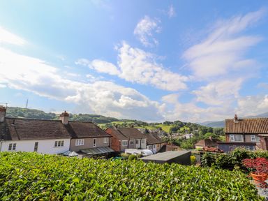 A residential area with houses and green hedges under a partly cloudy sky at Heddfan in Conwy