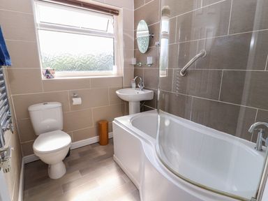 A bathroom with a toilet sink bathtub and a window at Heddfan Conwy