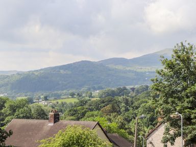 A view of rooftops and trees with hills in the background at Heddfan in Conwy