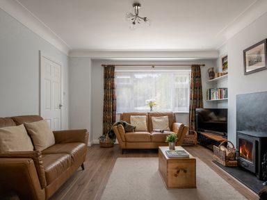A living room with brown leather sofas a wooden coffee table a fireplace and a television at Heddfan in Conwy