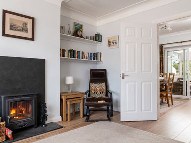 A sitting area with a chair and nested tables next to a fireplace and bookshelves at Heddfan in Conwy