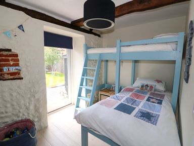 A bedroom with a blue bunk bed and a door leading to a garden at Far Barn in Fakenham