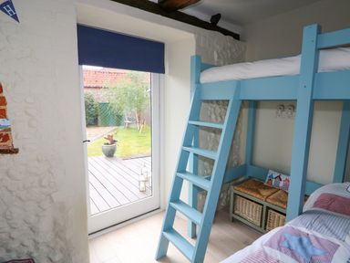A bedroom with a blue bunk bed and a glass door leading to a garden at Far Barn in Fakenham