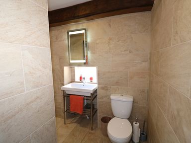 A bathroom with a toilet sink mirror and bathroom accessories at Far Barn in Fakenham
