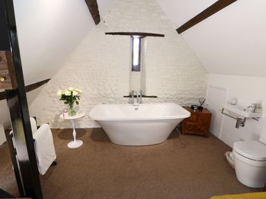 A bathroom with a freestanding bathtub towels and a toilet at Far Barn in Fakenham