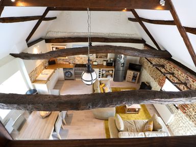 A kitchen and living area with wooden beams and a dining table at Far Barn in Fakenham