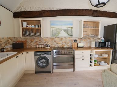 A kitchen with wooden countertop washing machine stove fridge and kitchenware at Far Barn in Fakenham