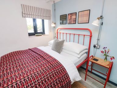 A bedroom with a red bed frame and side table at Grain Store near Narberth