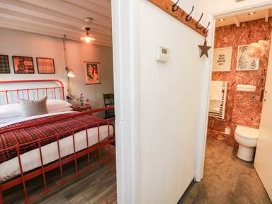 A bedroom with a red bed and access to a bathroom at Grain Store near Narberth