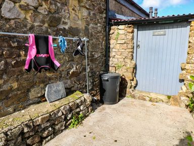 An outdoor area with wetsuit hanging and a laundry door at Grain Store near Narberth