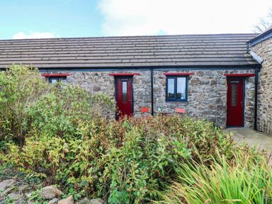 An outdoor area with stone walls and doors at Cattle Shed near Narberth