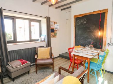 A dining area with colorful chairs and a chalkboard at Cattle Shed near Narberth