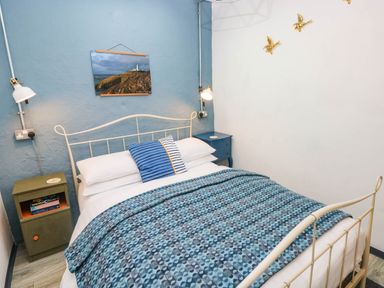 A bedroom with a bed, nightstand, lamp, and wall art at Cattle Shed near Narberth