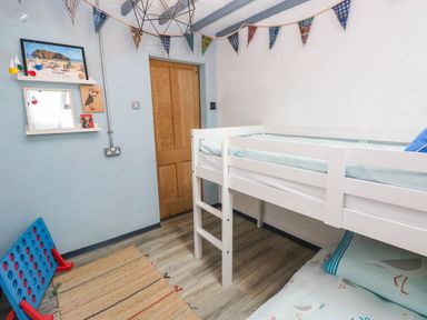 A bedroom with a loft bed, rug, and wall decorations at Cattle Shed near Narberth