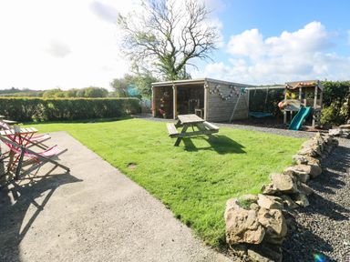 A garden with a picnic table and play area at Hayloft near Narberth
