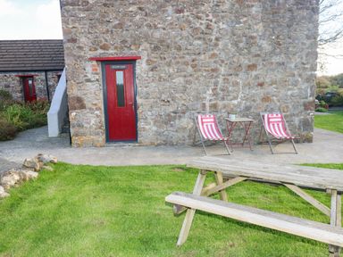 An outdoor area with a stone wall and seating at Milking Shed near Narberth