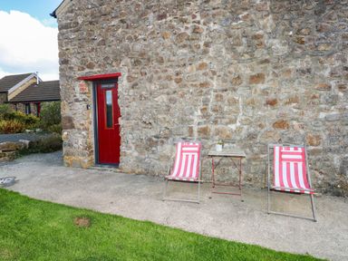 Two chairs and a table in front of a stone wall at Milking Shed near Narberth