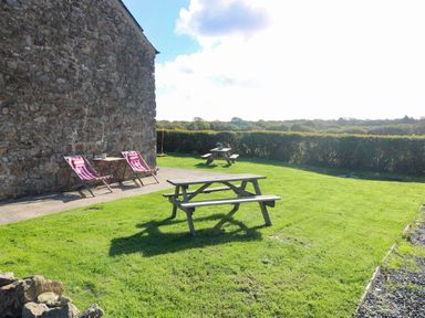 A garden with deck chairs and a picnic table at Milking Shed near Narberth