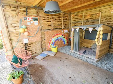 An indoor play area with a wooden playhouse and colorful decorations at Milking Shed near Narberth