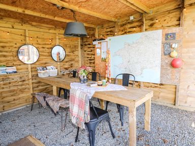 A dining area with a table and chairs with a map on the wall at Milking Shed near Narberth