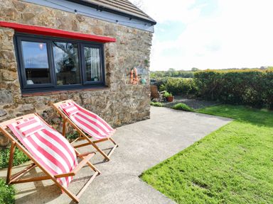A patio with deck chairs and a stone wall at Milking Shed near Narberth