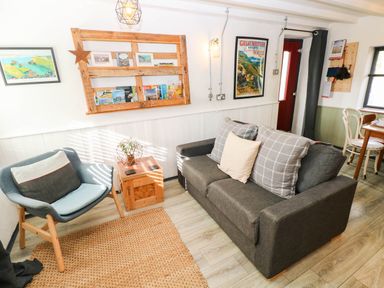 A living room with sofa, armchair, and shelf at Milking Shed near Narberth