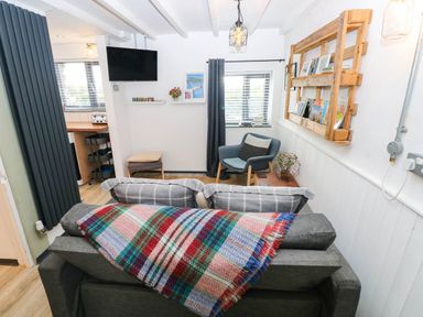A living room with a sofa, armchair, and television at Milking Shed near Narberth