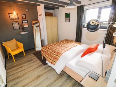 A bedroom with a bed and a yellow chair at Milking Shed near Narberth