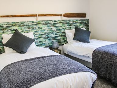 A bedroom with two single beds grey pillows and a wooden oar decoration at Meadow View in Meifod Powys