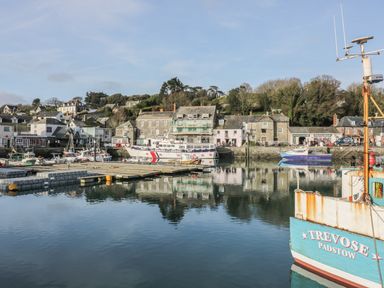 A harbor with boats docked and buildings along the waterfront at Chiffchaff in Padstow
