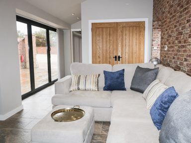 A living room with a beige sectional sofa with cushions and a brass tray on an ottoman at Owl View in Lebberston near Cayton