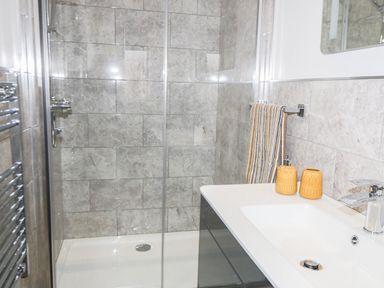 A bathroom with a tiled shower enclosure a sink with yellow soap dispensers and a striped towel at Owl View in Lebberston near Cayton